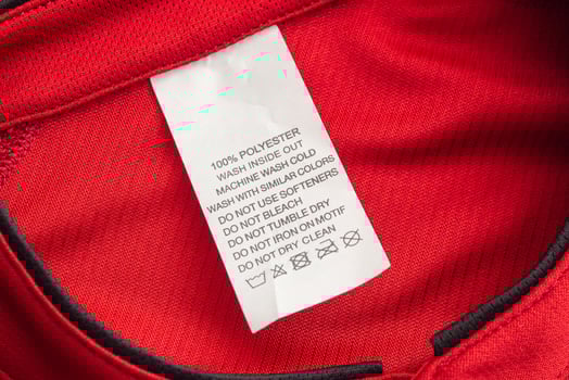 White laundry care washing instructions clothes label on red jersey polyester sport shirt photo