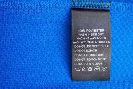 Black laundry care washing instructions clothes label on blue jersey polyester sport shirt photo