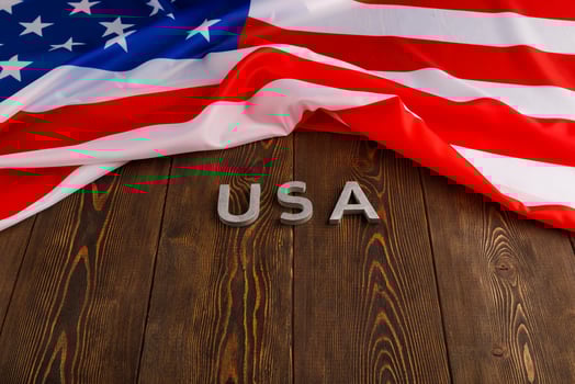 crumpled United States of America flag and with word USA laid with on flat textured wooden surface background photo