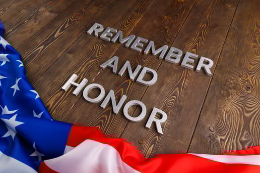 words remember and honor laid with silver metal letters on wooden background with USA flag underneath photo