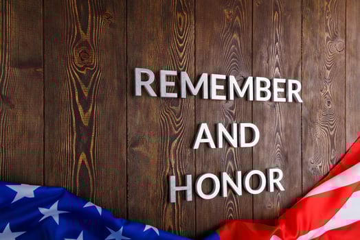 words remember and honor laid with silver metal letters on wooden background with USA flag underneath photo