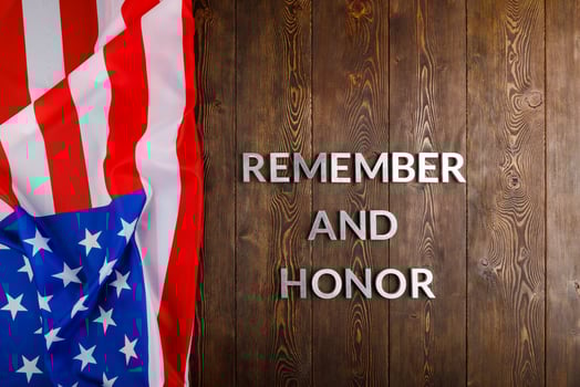 words remember and honor laid with silver metal letters on wooden background with USA flag on the left side photo