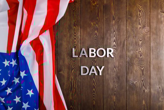 words labor day laid with silver metal letters on wooden surface with crumpled USA flag on left side photo