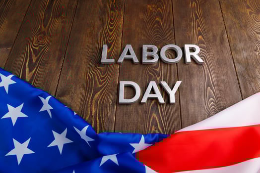 words labor day laid with silver metal letters on wooden surface with crumpled USA flag on bottom side photo