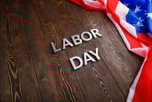 words labor day laid with silver metal letters on wooden surface with crumpled USA flag on left side photo