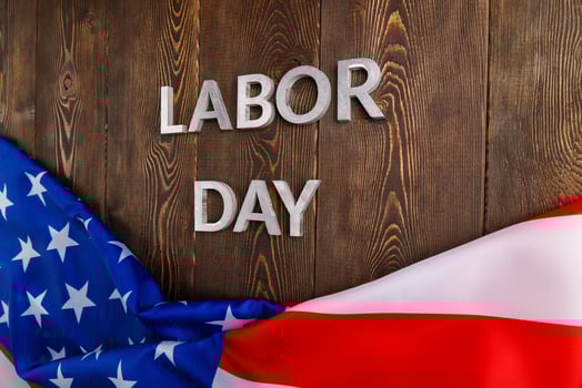 words labor day laid with silver metal letters on wooden surface with crumpled USA flag on bottom side photo
