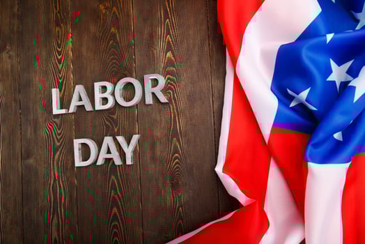 words labor day laid with silver metal letters on wooden surface with crumpled USA flag on left side photo