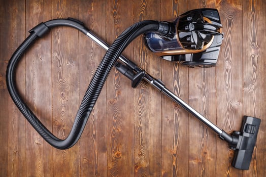 cheap cyclone bagless vacuum cleaner on wooden background in directly above view photo