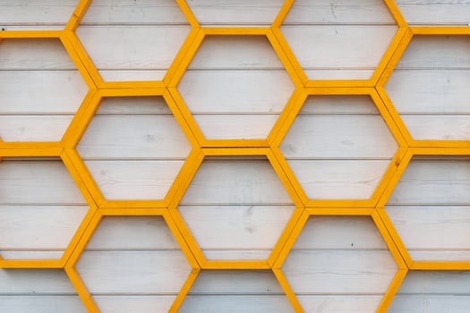 yellow honeycomb pattern wooden shelf on white painted wooden plank wall photo