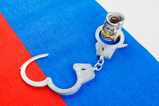 roll of us dollar banknotes in a handcuffs on flat full-frame russian flag photo