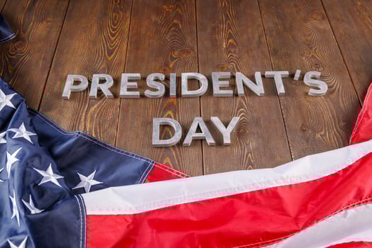 words presitdents day laid with silver letters on wooden surface near US flag photo