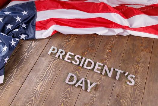words presitdents day laid with silver letters on wooden surface near US flag photo