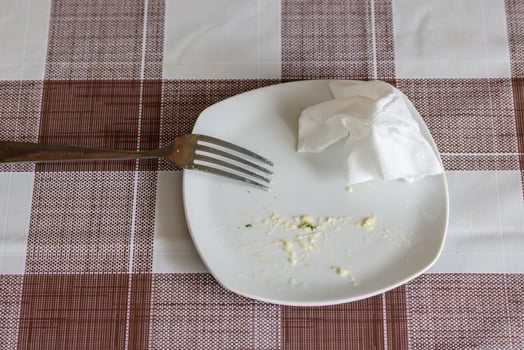empty white dish with leftovers of eaten food, crumpled table-napkin and steel fork photo