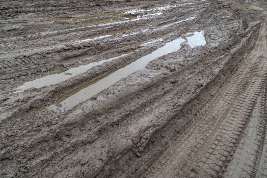 A broken rural country road after the rain. Puddles after rain on a dirt road. Clay, soil and puddles at cloudy day light after rain, autumn season. photo