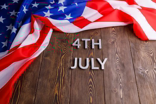 the words 4th july and crumpled usa flag on flat textured wooden surface background photo