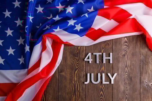 the words 4th july and crumpled usa flag on flat textured wooden surface background photo