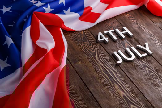 the words 4th july and crumpled usa flag on flat textured wooden surface background photo