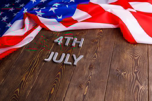 the words 4th july and crumpled usa flag on flat textured wooden surface background photo