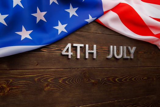 the words 4th july and crumpled usa flag on flat textured wooden surface background photo