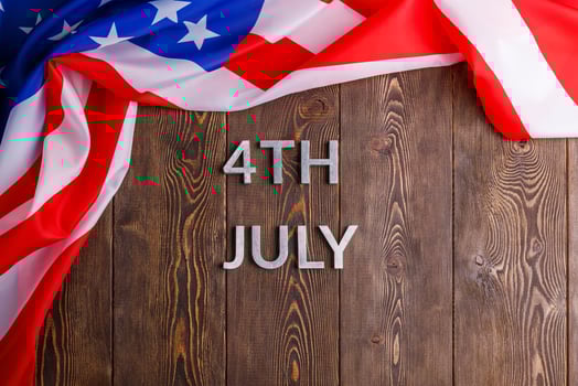 the words 4th july and crumpled usa flag on flat textured wooden surface background photo