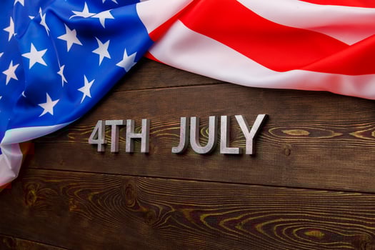 the words 4th july and crumpled usa flag on flat textured wooden surface background photo