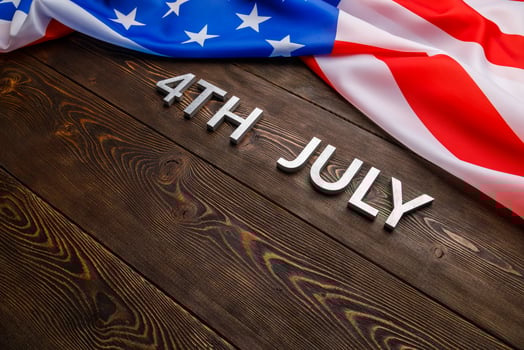 the words 4th july and crumpled usa flag on flat textured wooden surface background photo