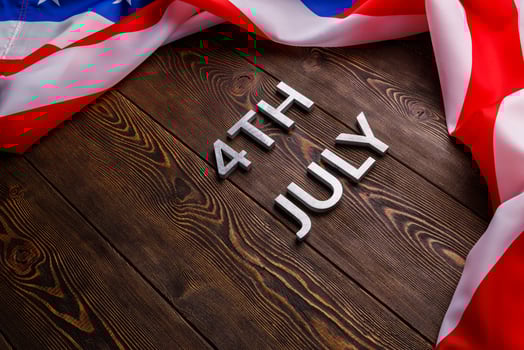 the words 4th july and crumpled usa flag on flat textured wooden surface background photo