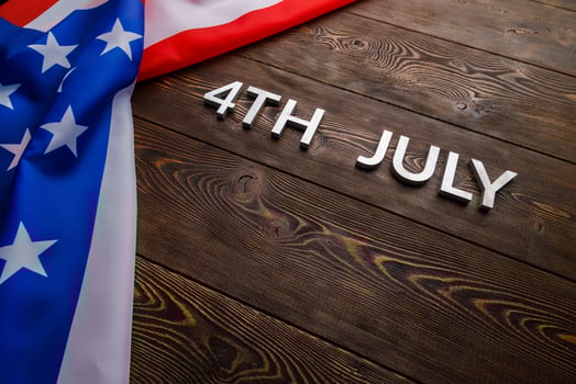 the words 4th july and crumpled usa flag on flat textured wooden surface background photo