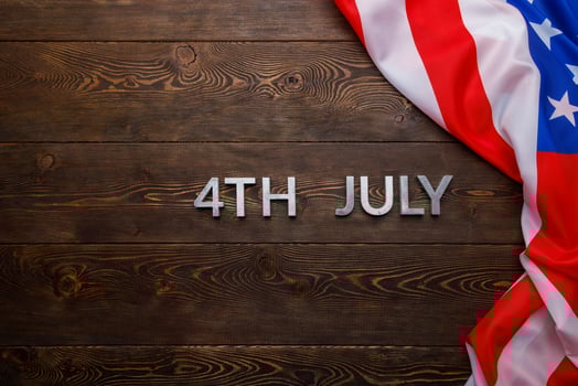 the words 4th july and crumpled usa flag on flat textured wooden surface background photo