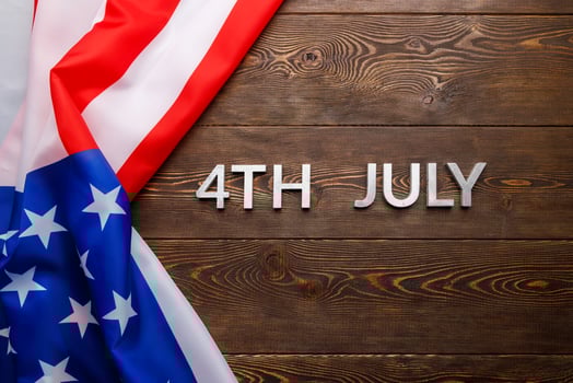 the words 4th july and crumpled usa flag on flat textured wooden surface background photo