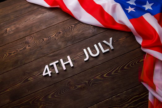 the words 4th july and crumpled usa flag on flat textured wooden surface background photo
