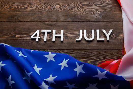 the words 4th july and crumpled usa flag on flat textured wooden surface background photo