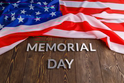the words memorial day laid with silver metal letters on wooden board surface with crumpled usa flag above photo