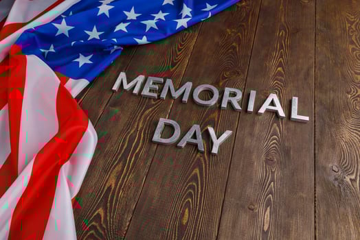 the words memorial day laid with silver metal letters on wooden board surface with crumpled usa flag photo
