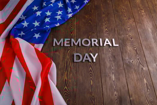 the words memorial day laid with silver metal letters on wooden board surface with crumpled usa flag photo