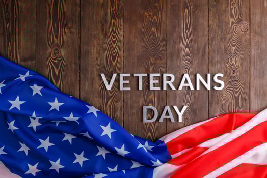 the words veterans day laid with silver metal letters on wooden board surface with crumpled usa flag photo