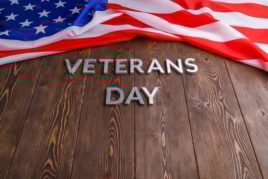 the words veterans day laid with silver metal letters on wooden board surface with crumpled usa flag photo