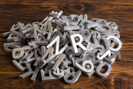 pile of silver metal alphabet characters cutted by waterjet machine in wooden background photo