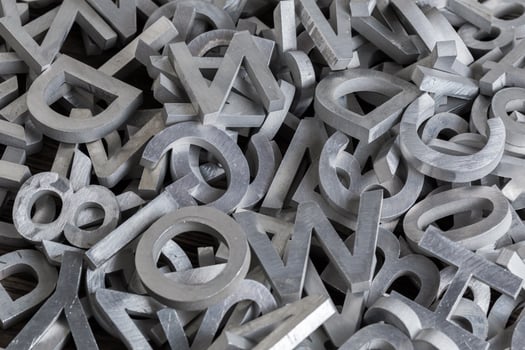 pile of white metal alphabet characters cutted by waterjet machine photo