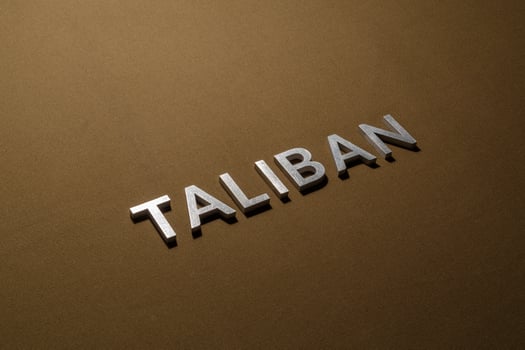 the word taliban laid with silver metal letters on rough tan khaki canvas fabric photo