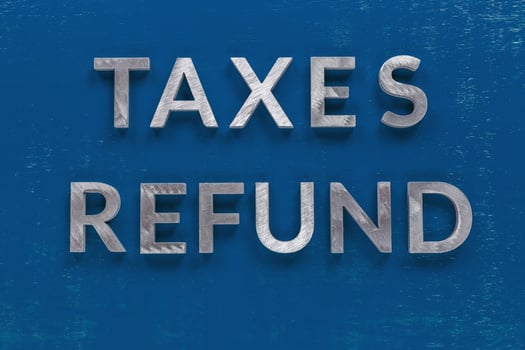 the words taxes refund laid on classic blue board with thick silver metal aphabet haracters photo