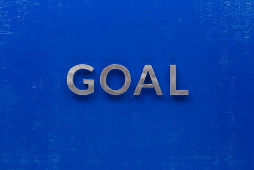 the word goal laid with silver metal characters on blue painted wooden board in central flat lay composition photo