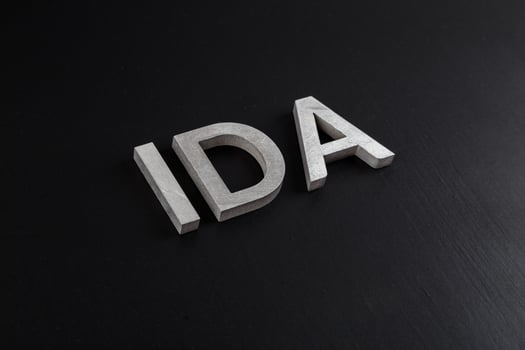 the word ida laid with silver metal letters over dry black matte surface photo