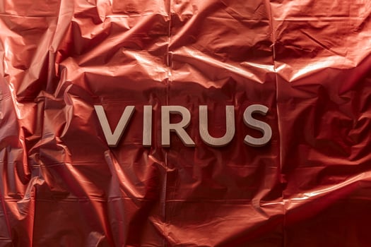 the word virus laid with silver metal letters on red background of crumpled plastic film with dramatic light photo