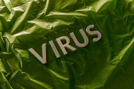 the word virus laid with silver metal letters on crumpled green plastic film with dramatic light photo