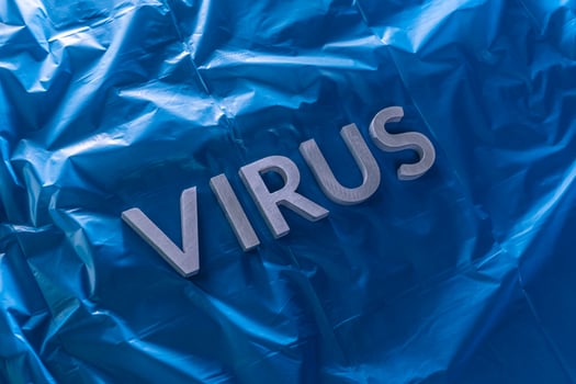 the word virus laid with silver metal letters on crumpled blue plastic film with dramatic light photo