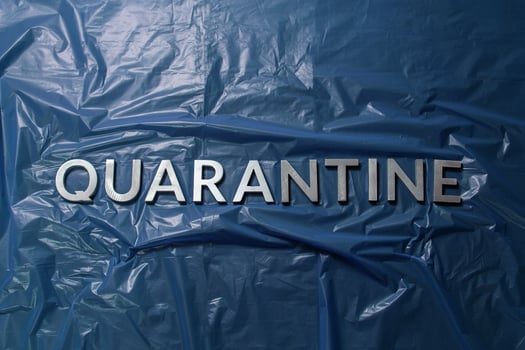 the word quarantine laid with silver letters on crumpled blue plastic film flat lay centered composition photo