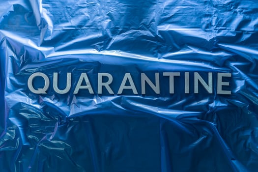 the word quarantine laid with silver letters on crumpled blue plastic film flat lay centered composition photo