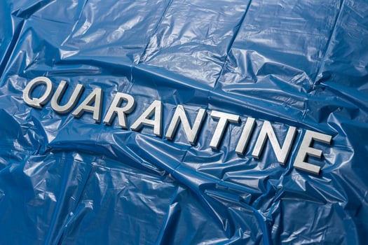 the word quarantine laid with silver letters on crumpled blue plastic film in diagonal perspective photo