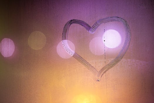 heart symbol hand drawn on wet night window glass in orange colors photo